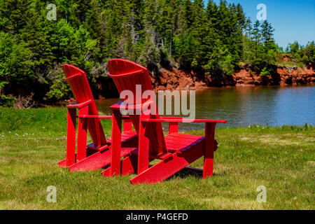 Rosso sedie Adirondack lungo le rive di Prince Edward Island, Canada. Foto Stock