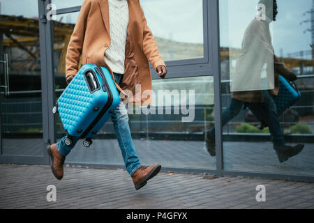 Immagine ritagliata di mezza età African American uomo fretta fino sul treno con una valigia Foto Stock