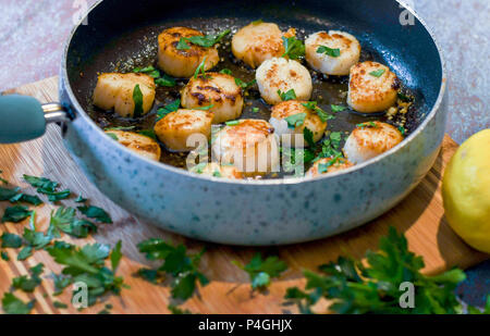 Capesante rosolare in una padella; fatta in casa il cibo gourmet Foto Stock