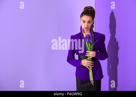 Moda African American Girl in posa nella camicia viola con iridi a ultra violet parete Foto Stock