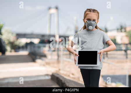 Bambino in maschera protettiva che mostra compressa sulla strada, inquinamento atmosferico concetto Foto Stock