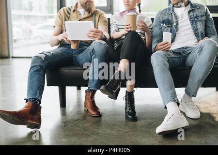 Vista ritagliata della gente di affari in appoggio e tenendo i gadget in luce moderno ufficio Foto Stock