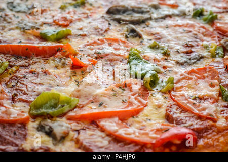 Pizza con salame, pomodori, pepe e funghi come sfondo. Riempito con telaio di pizza. Vista superiore Foto Stock