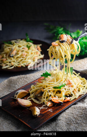 Pasta spaghetti con frutti di mare in una salsa cremosa su un tavolo in legno in stile rustico. Mediterraneo La cucina italiana. Foto Stock