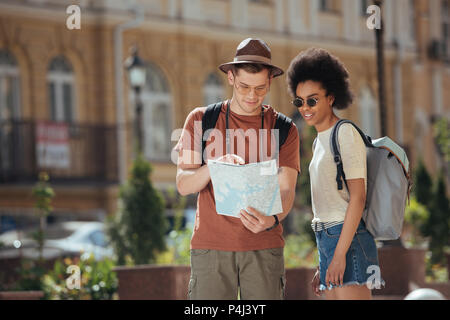 Giovane maschio traveler puntando alla mappa per americano africano ragazza in piedi accanto a Foto Stock