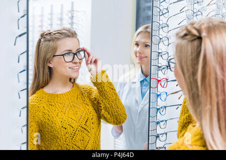 All'ottico optometrista femminile aiutando client a scegliere gli occhiali in ottica Foto Stock