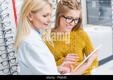 All'ottico optometrista con tavoletta digitale consentendo al cliente di scegliere gli occhiali in ottica Foto Stock