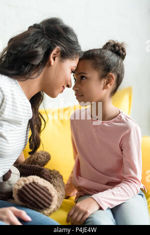 Madre e figlia guardando ogni altro e toccando con fronte a casa Foto Stock