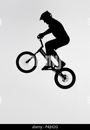 Silhouette di trial biker salto sulla bicicletta su bianco Foto Stock