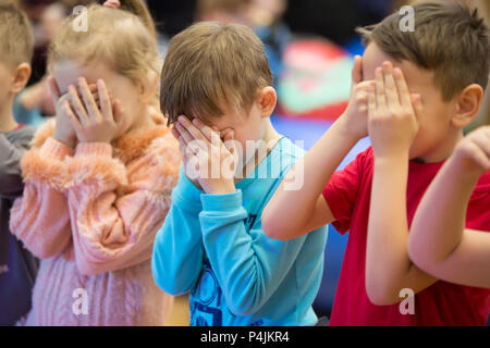 La Bielorussia, Gomel, il 10 marzo 2018. I bambini di vacanza all'apertura del negozio Caravan.I bambini coperti gli occhi con le mani. Foto Stock