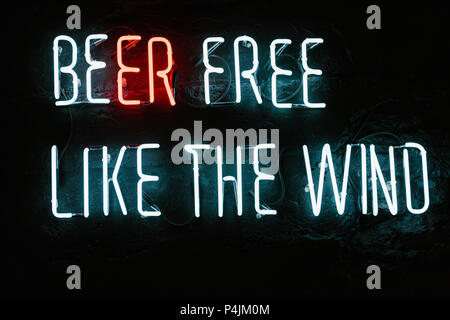 La birra libera come il vento neon iscrizione sulla parete scura in bar Foto Stock