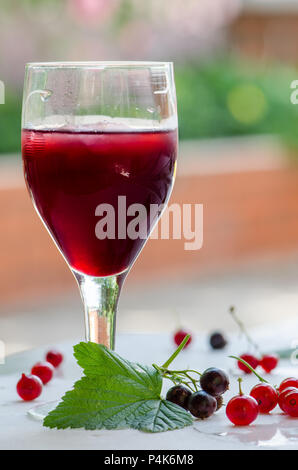 Crème de Cassis - ribes e ribes rosso liquore casalingo sullo sfondo luminoso Foto Stock