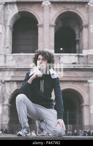 Vintage cerca immagine del bel giovane sportivo rilassante dopo la formazione con un asciugamano intorno al suo collo davanti al Colosseo a Roma Foto Stock