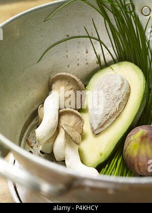 Avocado, funghi, fichi e erba cipollina in uno scolapasta Foto Stock