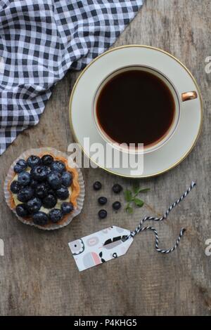 Una tazza di caffè e un mirtillo tartlet Foto Stock
