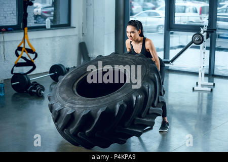 Forte donna sportivo ribaltamento ruota di allenamento in palestra Foto Stock