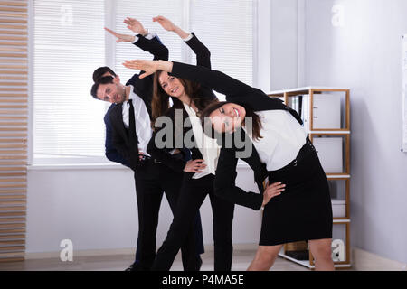 Giovani imprenditori in piedi in fila facendo esercizio al lavoro Foto Stock