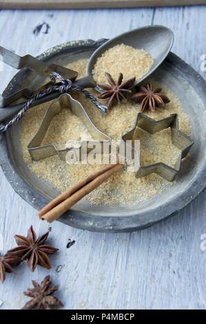 Una piastra con cookie cutter, un cucchiaio di zucchero, anice stellato e una stecca di cannella Foto Stock