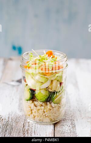 Insalata in un bicchiere con cuscus, i cavoli di Bruxelles, Apple, cicoria, carote e germogli di lenticchie Foto Stock