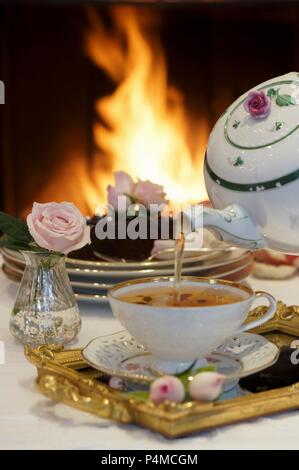 Bollitore per tè e torta al cioccolato davanti ad un fuoco aperto Foto Stock