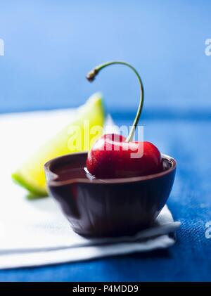 Una ciliegia in alcol in una piccola ciotola fatta di cioccolato Foto Stock