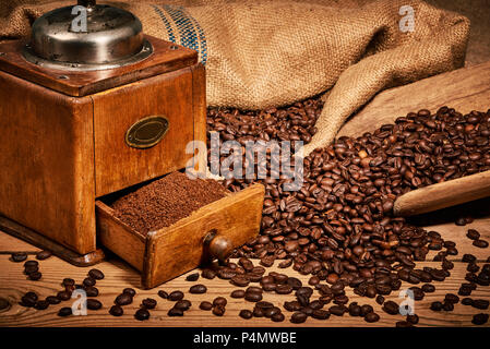 Il caffè con il vecchio macinino da caffè e fagioli sul tavolo di legno Foto Stock