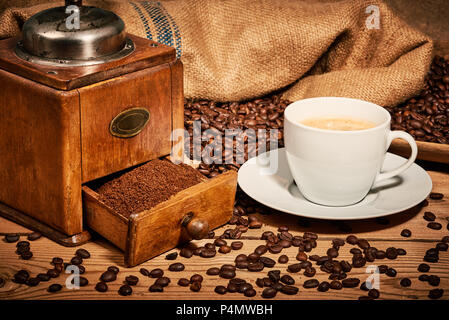 Tazza di caffè e la vecchia macchina di molatura con due cubetti