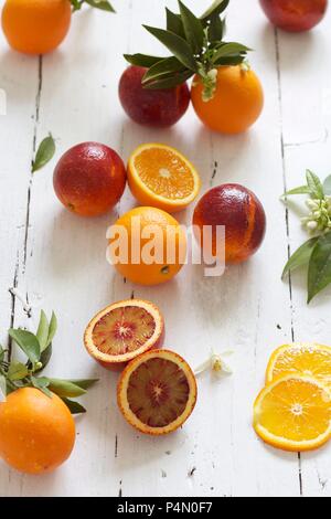 Arance e arance rosse con foglie Foto Stock