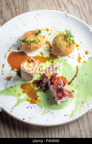 Arrosto di coniglio selvatico con pancetta croccante e farcite di riso arancini di sfere e una dolce pisello verde e salsa gravy Foto Stock