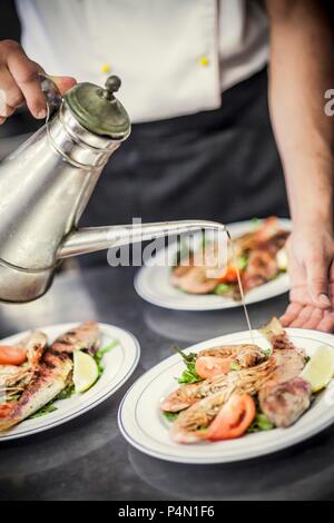 Rifiniti a mano grigliate di pesce e gamberetti su una piastra con olio di oliva Foto Stock