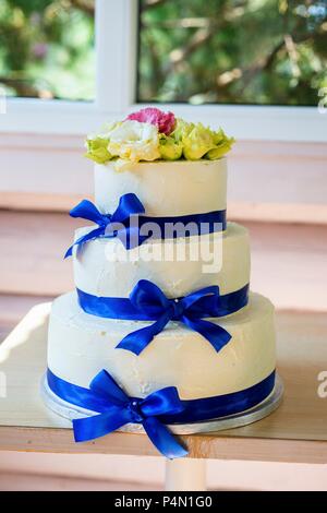 Una tre-tiered crema di burro torta di nozze con blu di nastri di seta Foto Stock