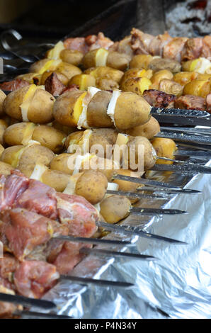 La carne cruda e le patate sono piantati su spiedini di metallo. Il processo di cottura shish kebab. Russo e ucraino cibo camp Foto Stock