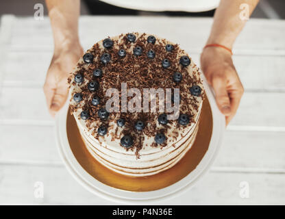 Giovane uomo attraente decorazione torta di cioccolato e frutti di bosco Foto Stock