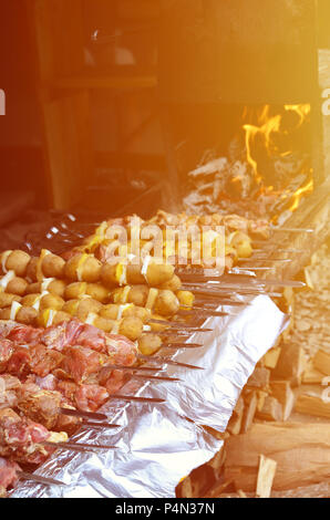 La carne cruda e le patate sono piantati su spiedini di metallo. Il processo di cottura shish kebab. Russo e ucraino cibo camp Foto Stock