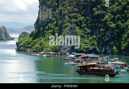 Villaggio galleggiante e imbarcazioni turistiche presso la famosa baia di Halong area in Vietnam, in Asia Foto Stock