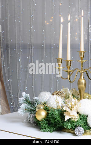 Nuovo Anno di decorazioni e un candelabro d'oro con candele accese in piedi sulla superficie di un pianoforte a coda . Foto Stock