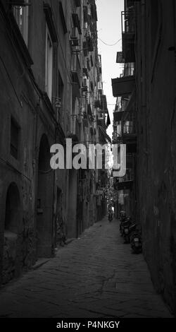 Napoli, Italia - Agosto 9, 2015: foto in bianco e nero, la gente comune a piedi su sporco buia stradina nel centro storico di Napoli Foto Stock