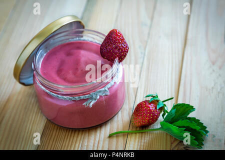 In un piatto di vetro sul tavolo frullato fragole in un vasetto con un coperchio. Foto Stock