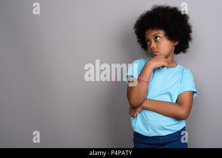 Giovane carina ragazza africana contro uno sfondo grigio Foto Stock