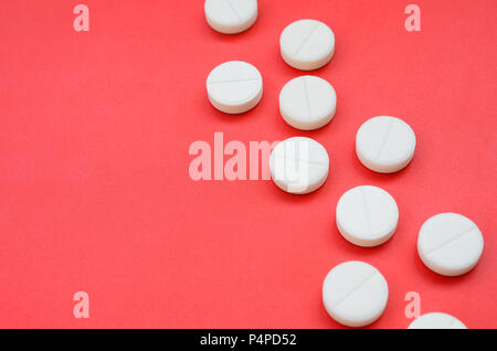 Un paio di compresse bianche giacciono su un rosso brillante superficie di sfondo. Immagine di sfondo sul farmaceutico e medico argomenti . Foto Stock