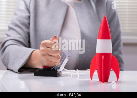 Imprenditrice la mano a razzo di lancio premendo il pulsante rosso Foto Stock