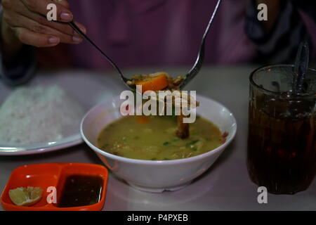 Deliziosa Nasi Soto, l'Indonesiano tradizionale cibo servito con riso e Ice Tea Foto Stock