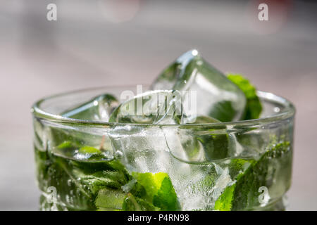 Rametti di menta verde in mojito con fettine di lime, i cubetti di ghiaccio, paglia, macro, texture, le sfocature Foto Stock