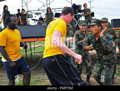 Stati Uniti I marinai e i Royal Marines Thai danza come membri della Royal Thai Marine Corps Band eseguire durante una giornata di sport e barbeque come parte della cooperazione a galla la prontezza e la formazione (Carati) Thailandia 2010 in Sattahip, Thailandia, 17 maggio 2010. Carato è una serie di accordi bilaterali di esercizi che si svolgono annualmente nel sud-est asiatico per rafforzare le relazioni e a migliorare la disponibilità di forza. (DoD Foto Stock