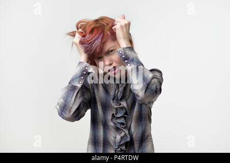 Ritratto di insolita piuttosto informale di donna con capelli colorati in cattivo umore frustrati. Lei tiene i suoi capelli. Negativo emozione per il viso. Foto Stock