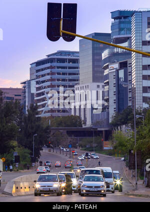 Johannesburg, Sud Africa, 12 maggio - 2018: automobili in attesa ad un semaforo con edifici per uffici in background. Foto Stock