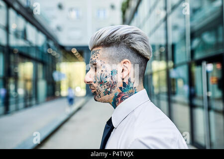 Giovane imprenditore con faccia tatuata, ritratto Foto Stock