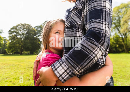 Figlia abbracciando la madre in un parco Foto Stock