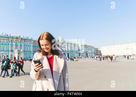 La Russia, San Pietroburgo, giovane donna utilizza lo smartphone nella città Foto Stock