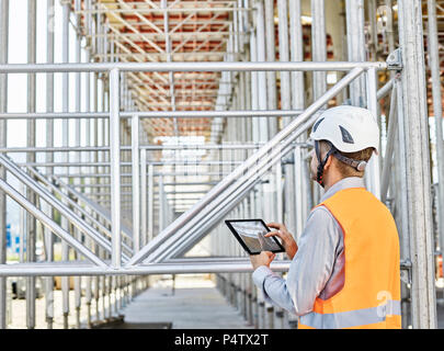 Architetto con tablet indossando il casco sul sito in costruzione Foto Stock